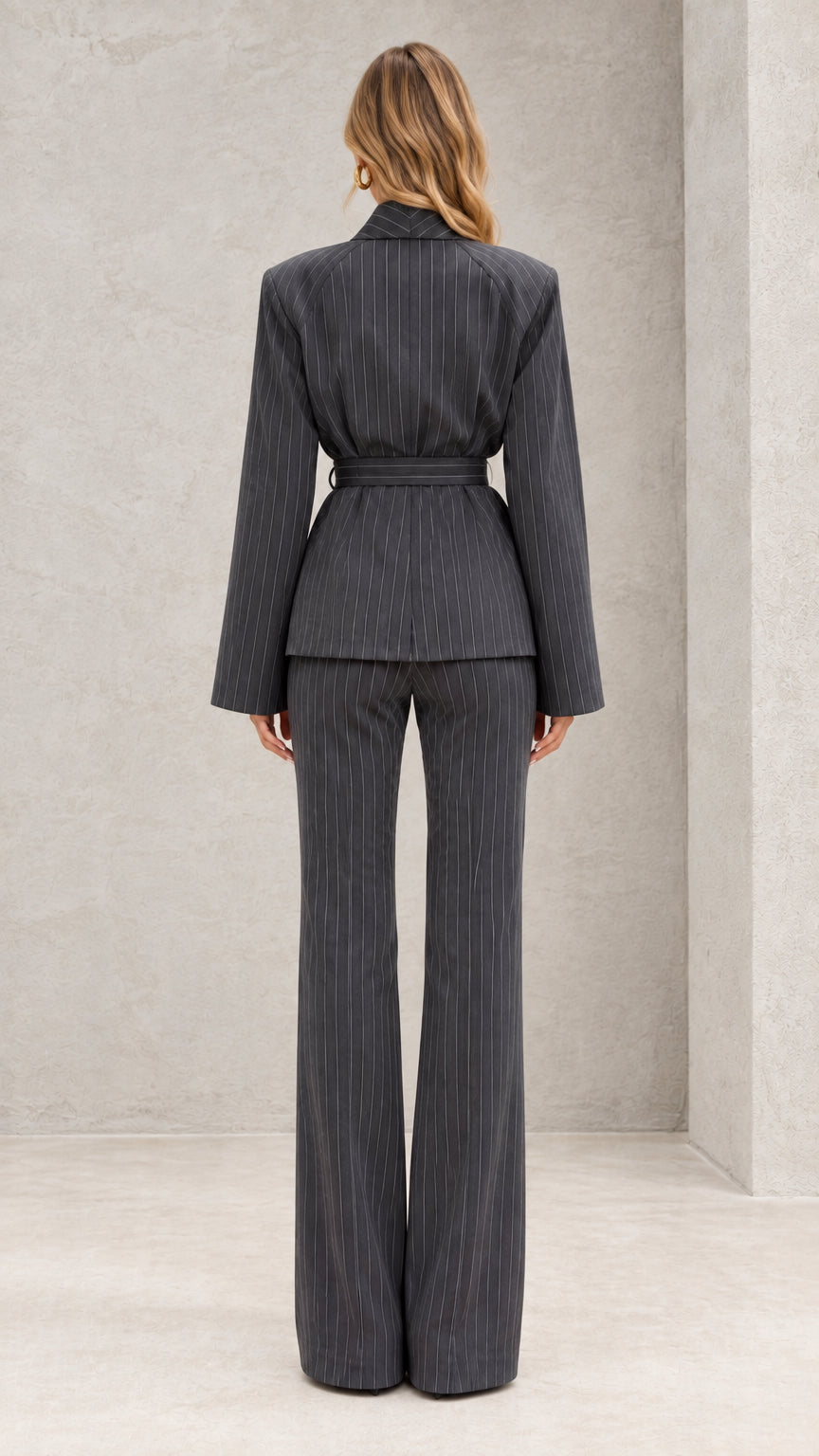 Back view of model wearing charcoal grey pinstripe wrap blazer and flare trousers