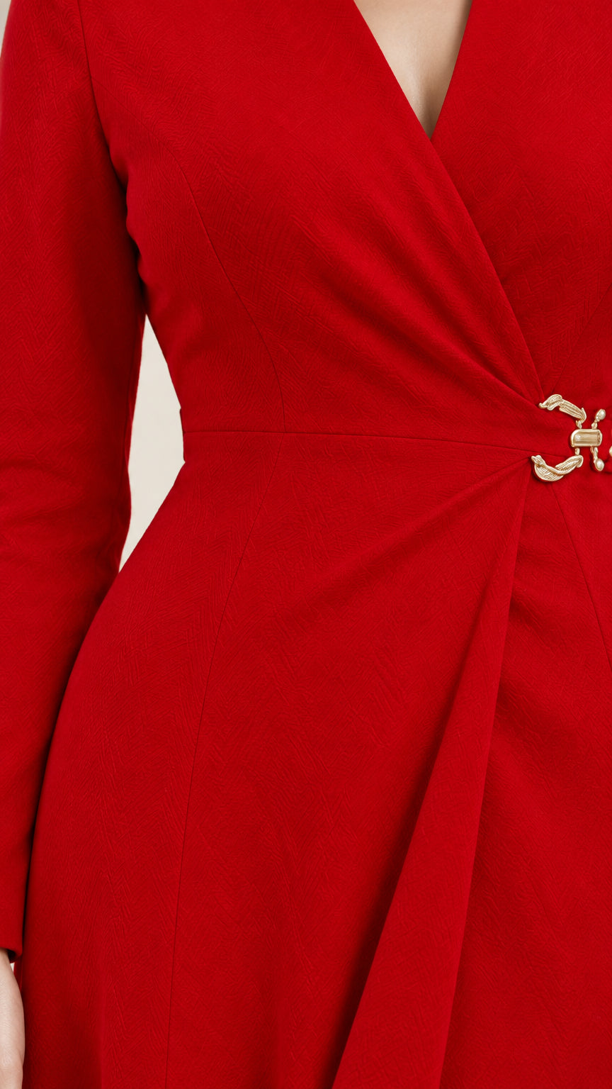 Close-up detail of side waist pleats and gold-tone buckle clasp on red wrap dress