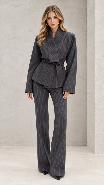 Front view of model wearing charcoal grey pinstripe belted wrap blazer and flare pants suit
