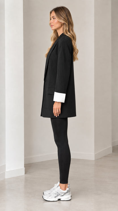 Side profile view of black pinstripe oversized blazer paired with black leggings and sneakers