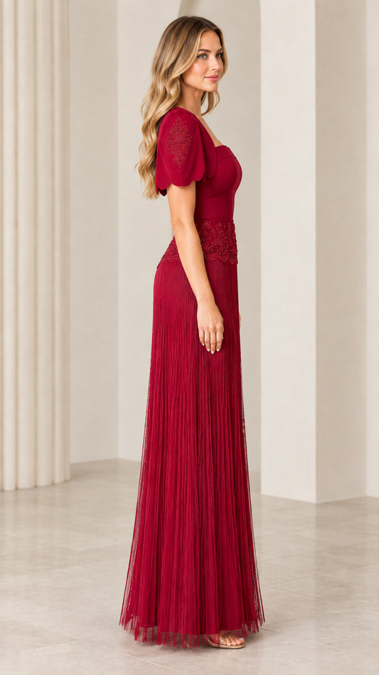Side profile view of woman wearing burgundy pleated maxi evening dress