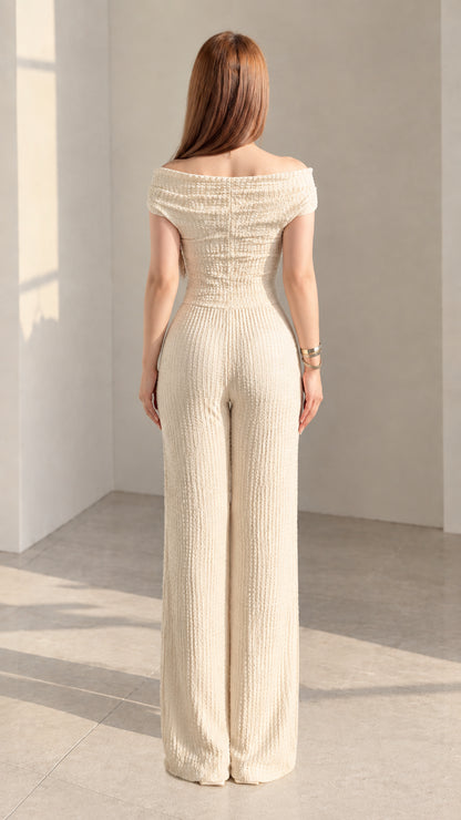 Back view of woman wearing cream textured off-shoulder top and wide-leg pants