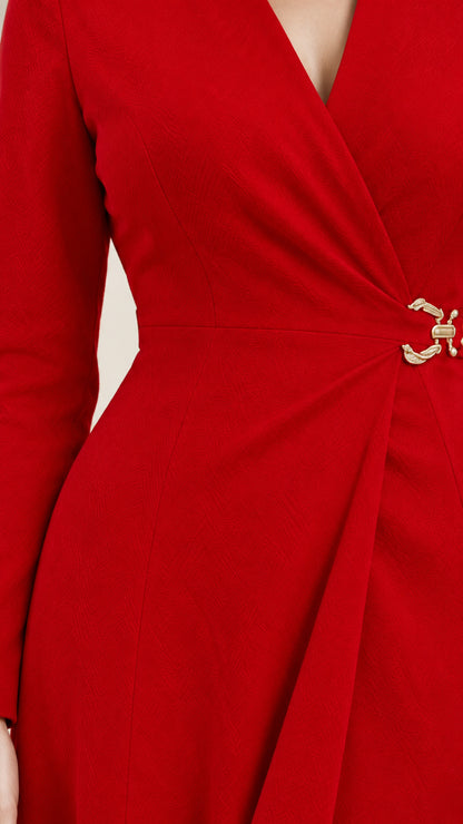Close-up detail of side waist pleats and gold-tone buckle clasp on red wrap dress